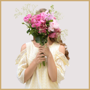 Image of a young women holding a bunch of pink flowers in front of her face