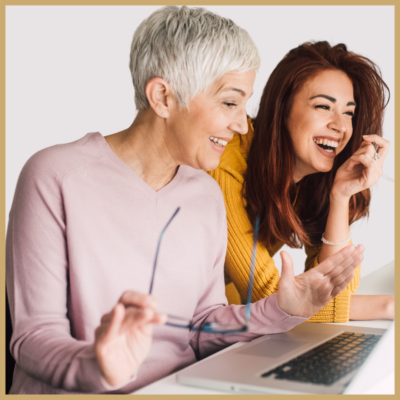 Two women smiling and collaborating on a writing project