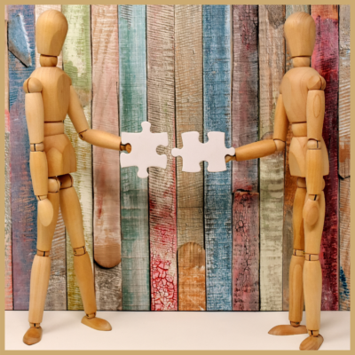 Two artist mannequins side by side, holding puzzle pieces towards each other.